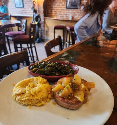 Pork chop with apple compote, grits, greens.